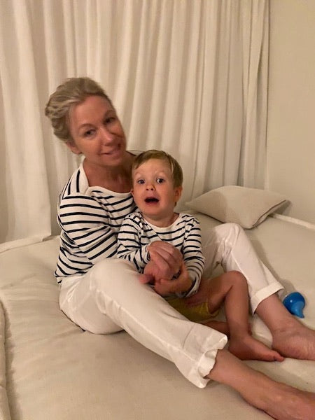 The founder, a mum herself, sitting with her young child in coordinating striped tops and relaxed white trousers — embodying the real-life inspiration behind our maternity clothes.