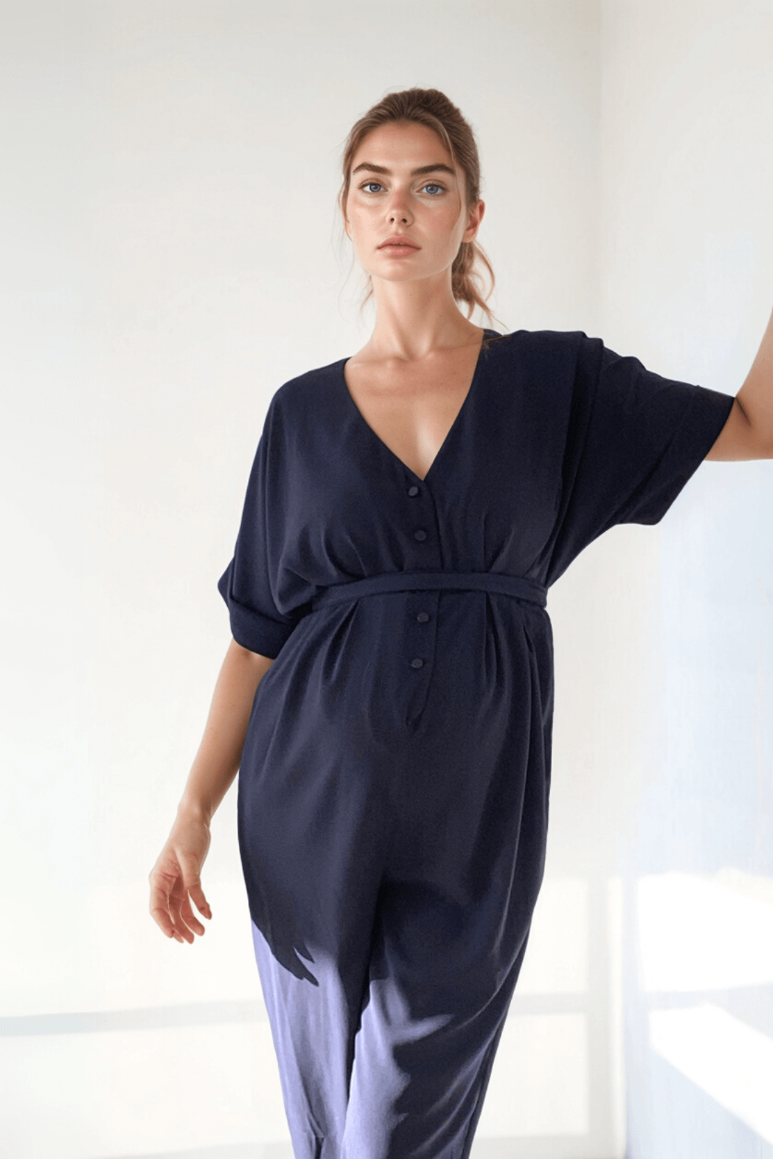 Woman wearing a navy blue jumpsuit styled as smart maternity wear and maternity office clothes, against a white background.