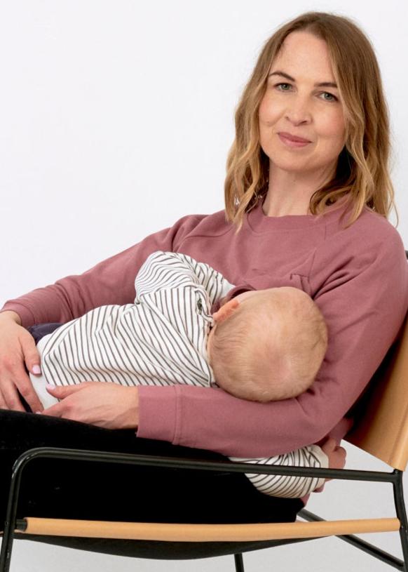 new mother breastfeeding her baby in a cafe wearing a nursing top with discreet zips that give better privacy coverage than a breastfeeding cover - stylish contemporary postpartum outfit idea